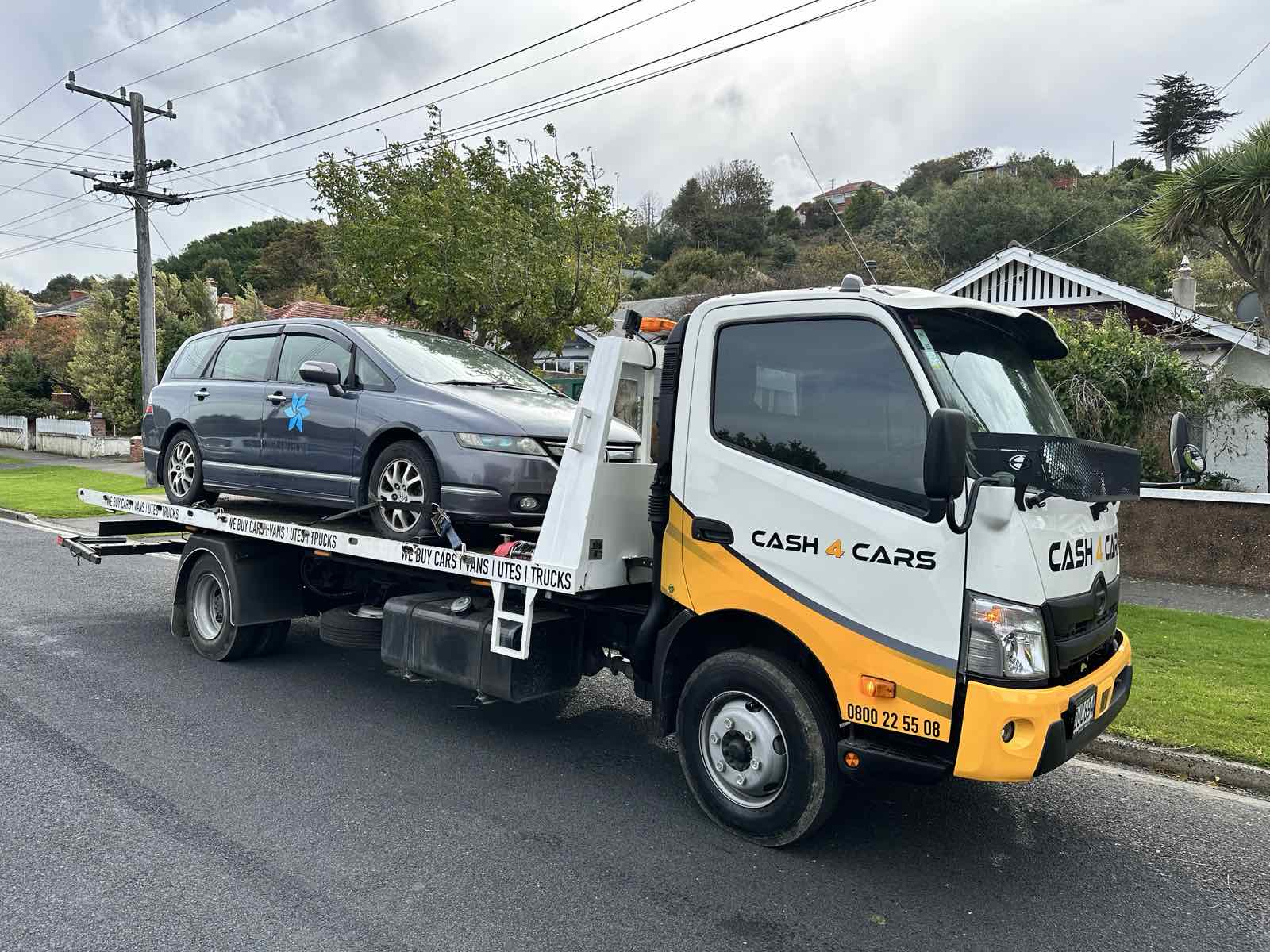 Cash 4 Cars truck collecting a grey station wagon from a residential street