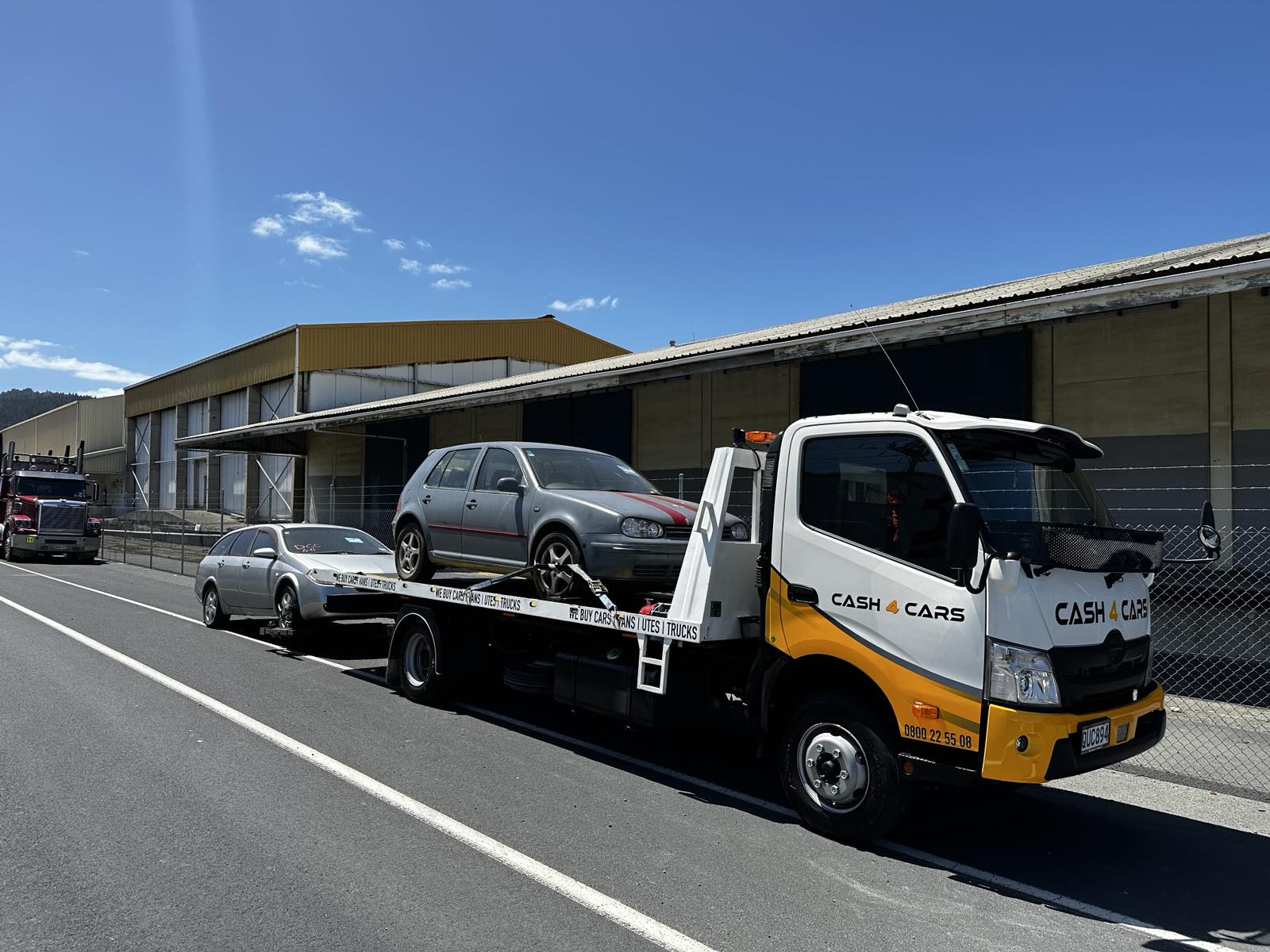 Cash 4 Cars flatbed truck transporting a hatchback for vehicle removal
