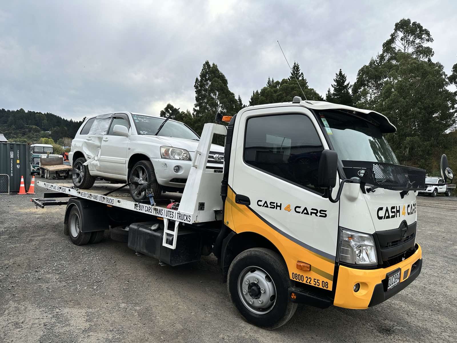 Cash 4 Cars flatbed carrying a white SUV for vehicle removal